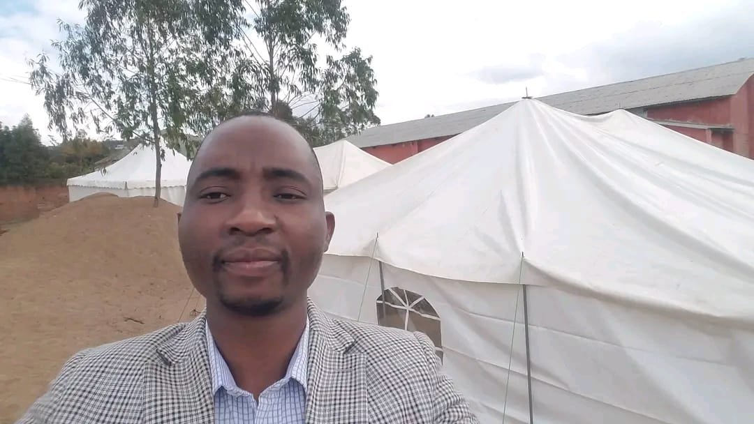 An outdoor selfie beside a large white tent.