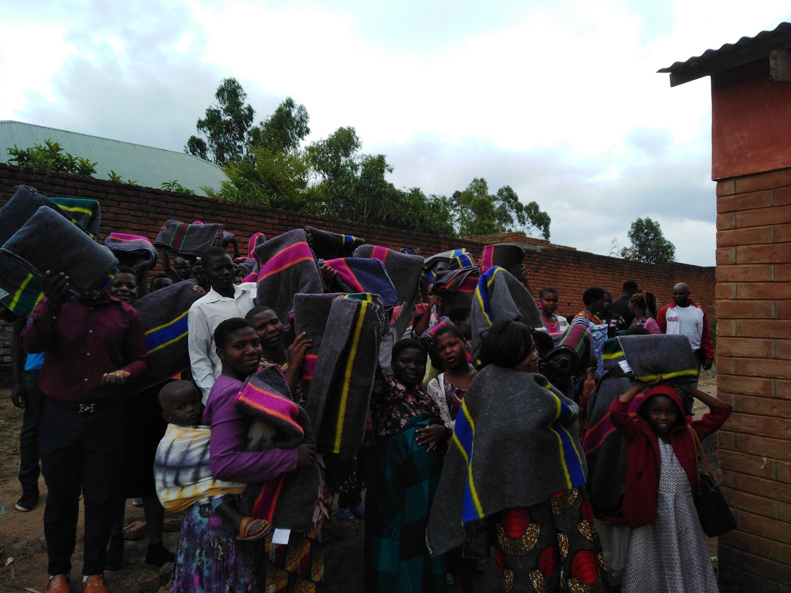 A wider view of the group holding blankets in an outdoor courtyard.