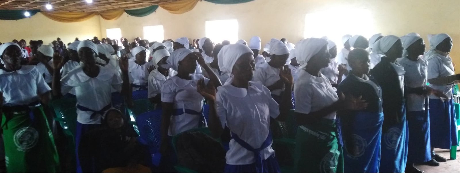 A wider view of women in blue and white clothing during an indoor gathering.