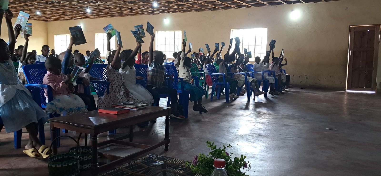 A wider view of the congregation holding up printed materials.