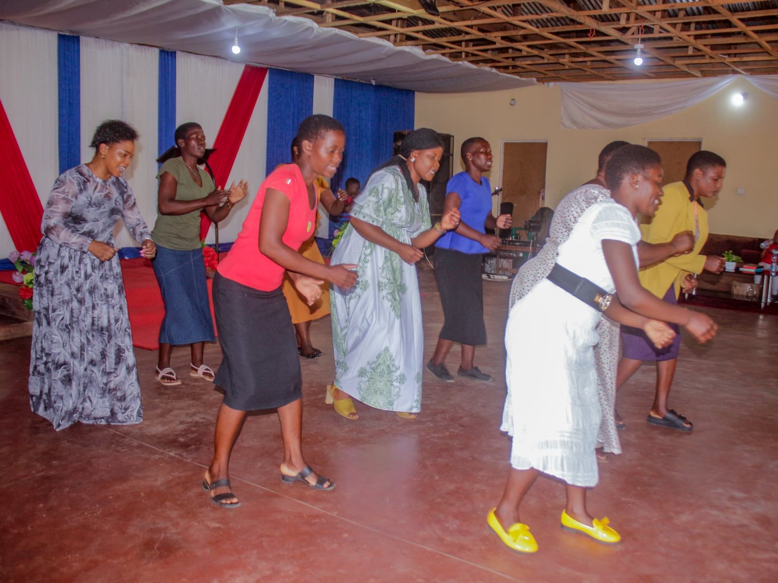 Women and young people take part in a group presentation inside the hall.