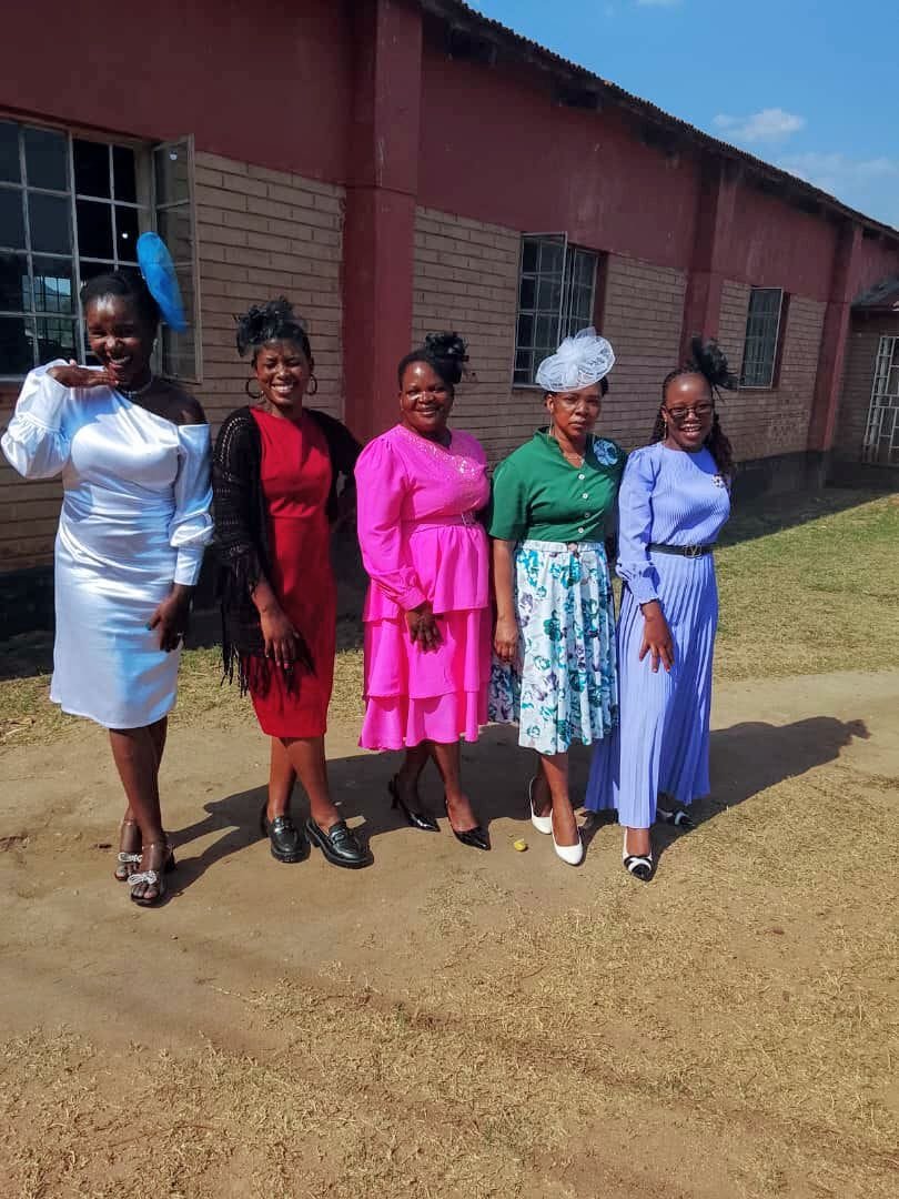 Five women pose outside the brick building.
